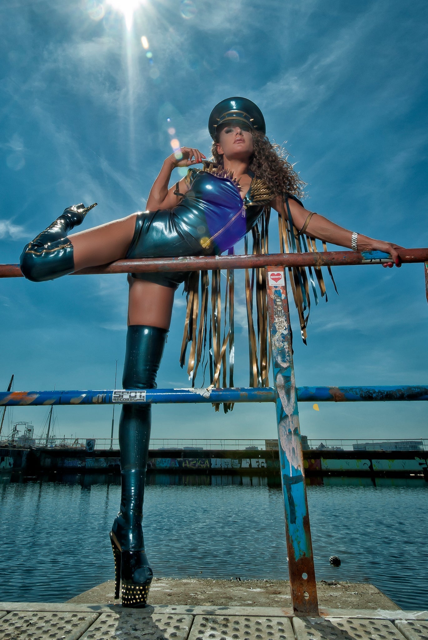 latex Biker sleeveless gilet jacket with fringing and a zip front on a model standing also wearing Latex zip up stockings